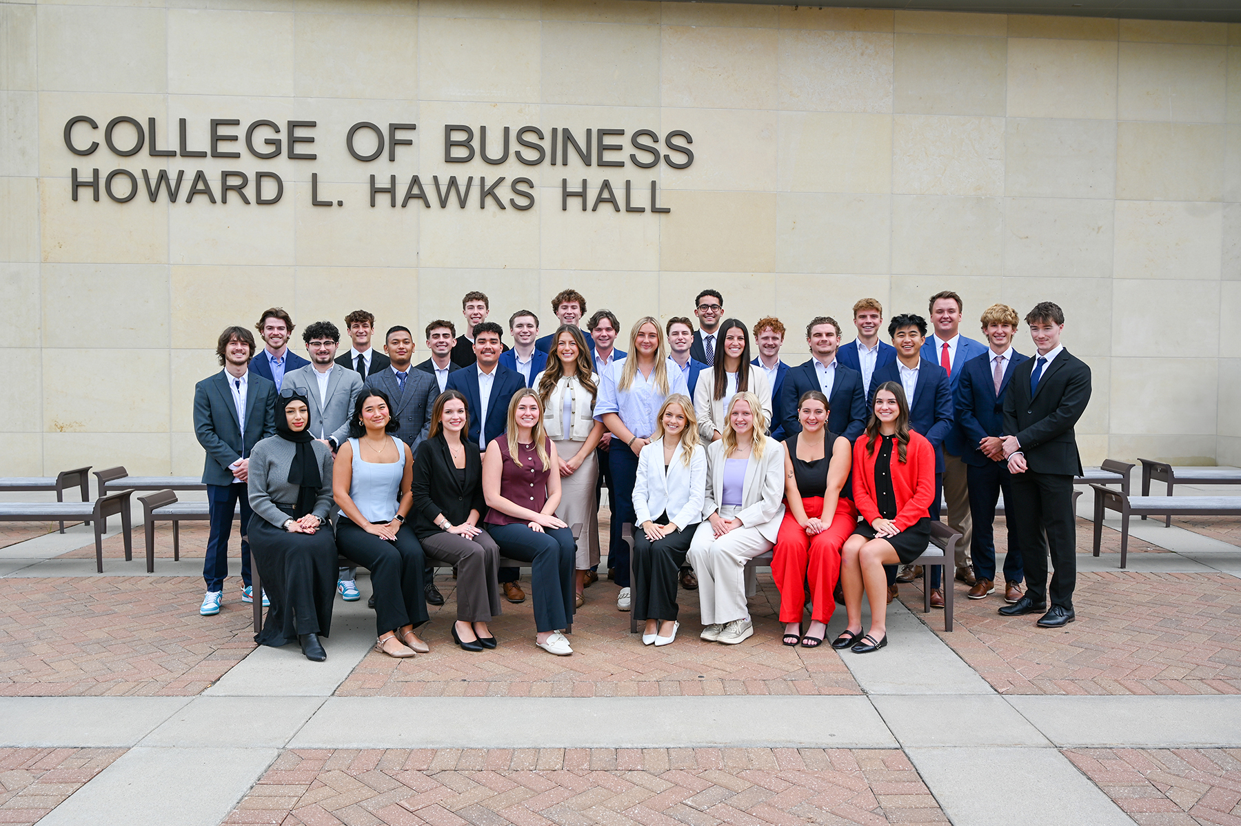 Thirty-one students — all members of the 10th cohort of the Clifton Builders Program at the University of Nebraska–Lincon — pose for an outdoor photograph in formal attire on the west side of Howard L. Hawks Hall.
