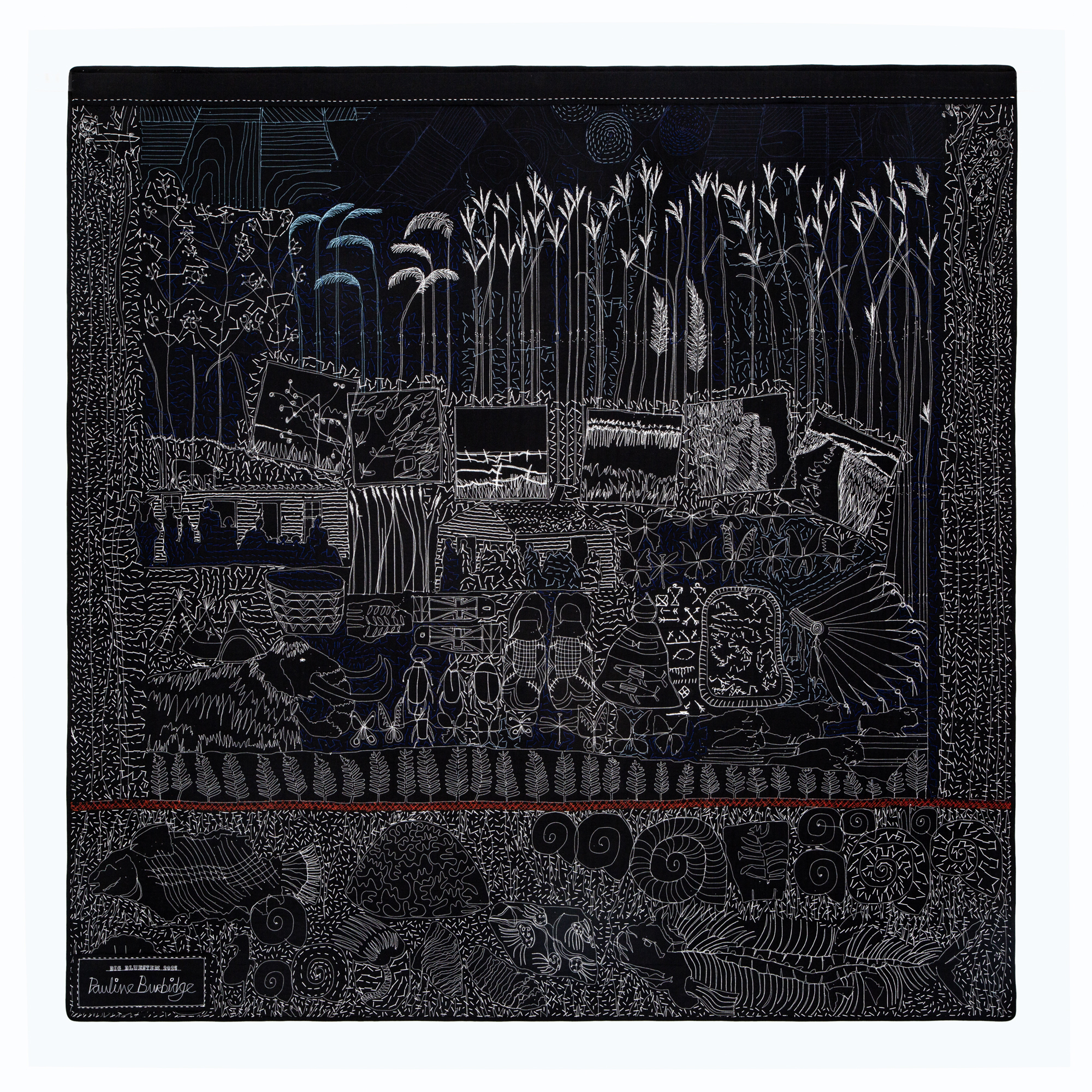 A black quilt backing with white stitches showing prairie grasses, a woolly mammoth, Native imagery and fossils.