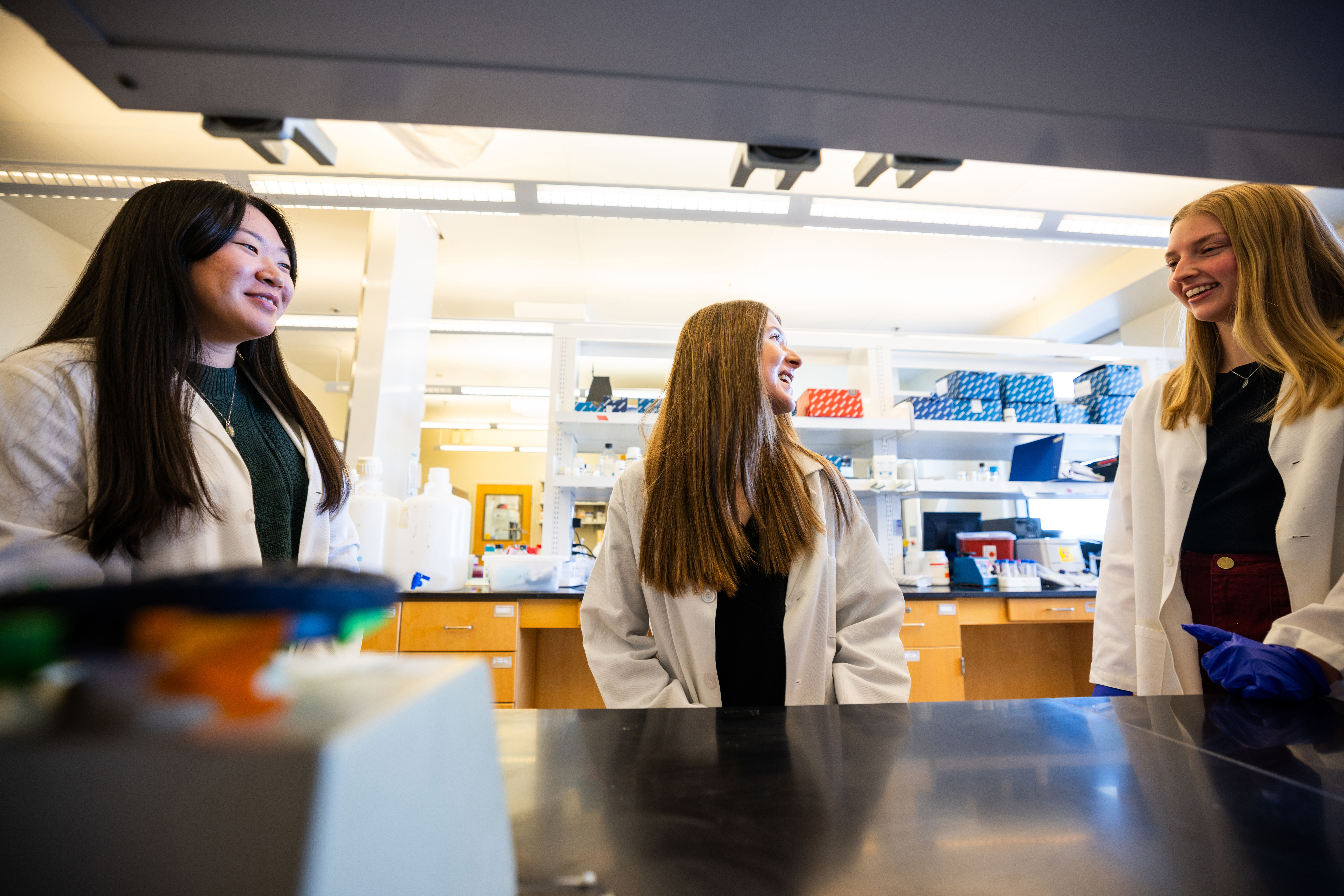 Husker undergraduates and UCARE participants (from left) Chanasei Ziemann, Vanessa Hubing and Avery Marquis pose in lab coats for a photo in Luwen Zhang’s campus lab.