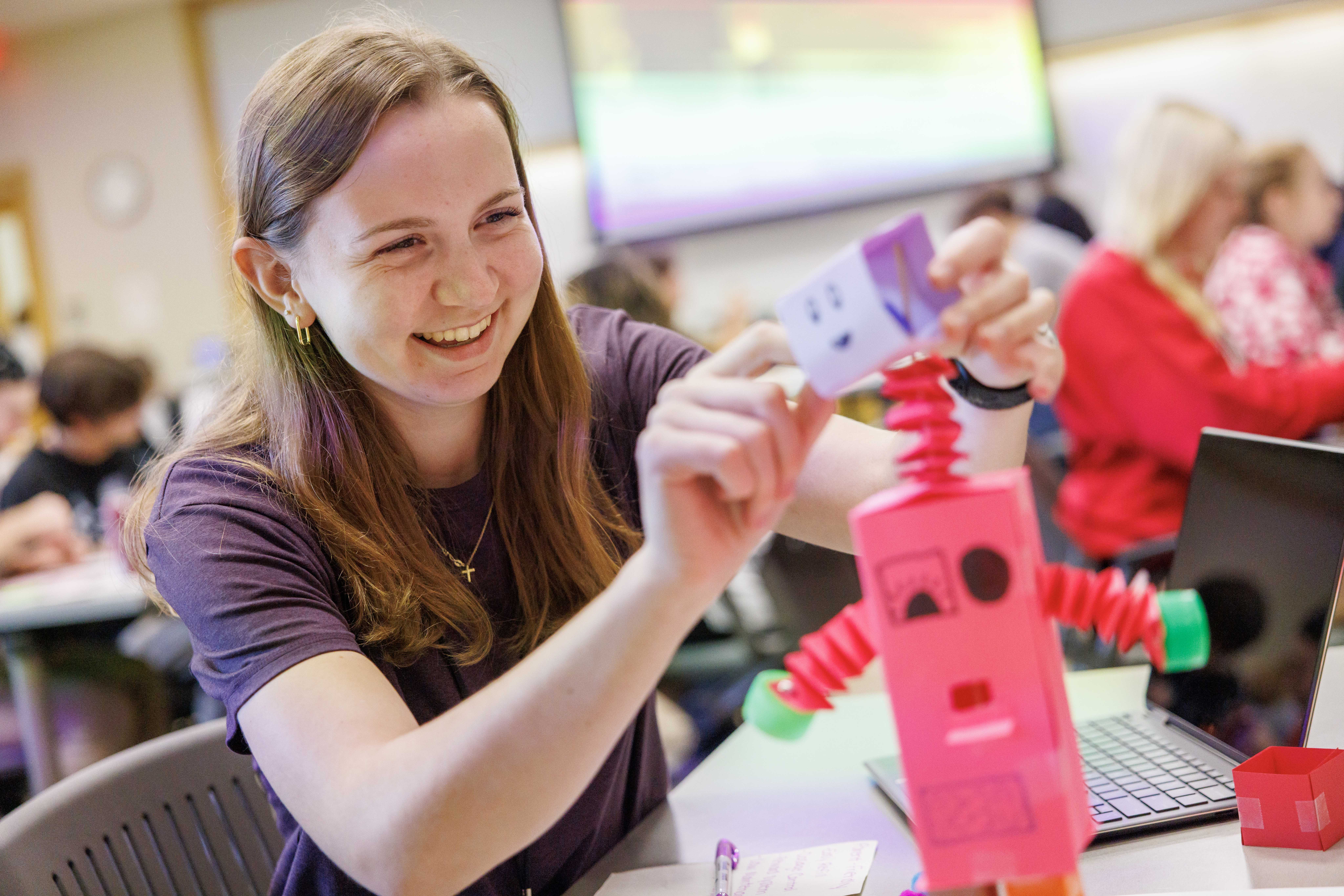 Bethany Miller, a junior hospitality, restaurant and tourism management major, works on a paper, vitamin-dispensing robot inside Howard L. Hawks Hall.
