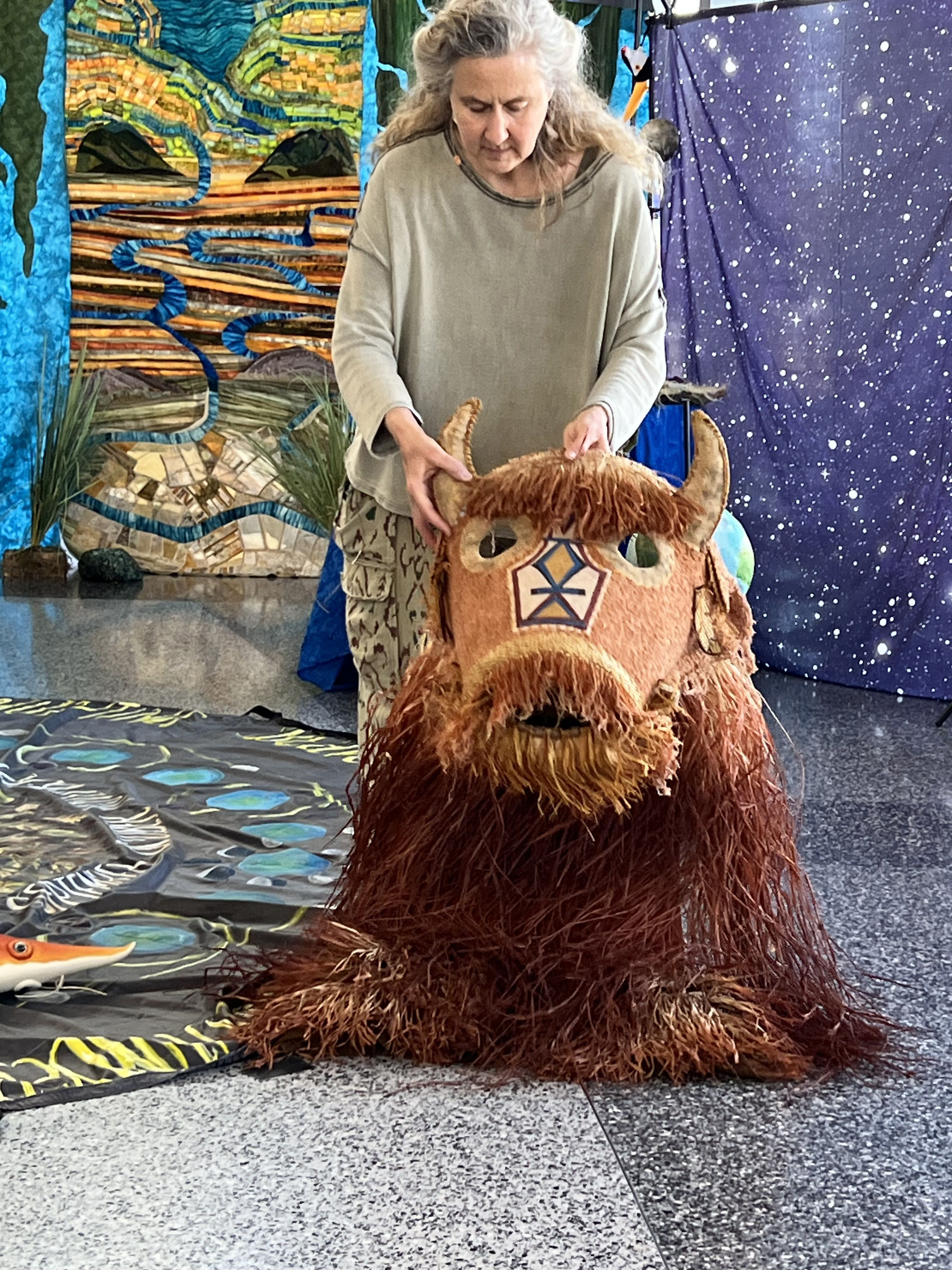 Heather Henson stands with a bison puppet in front of colorful backdrops.