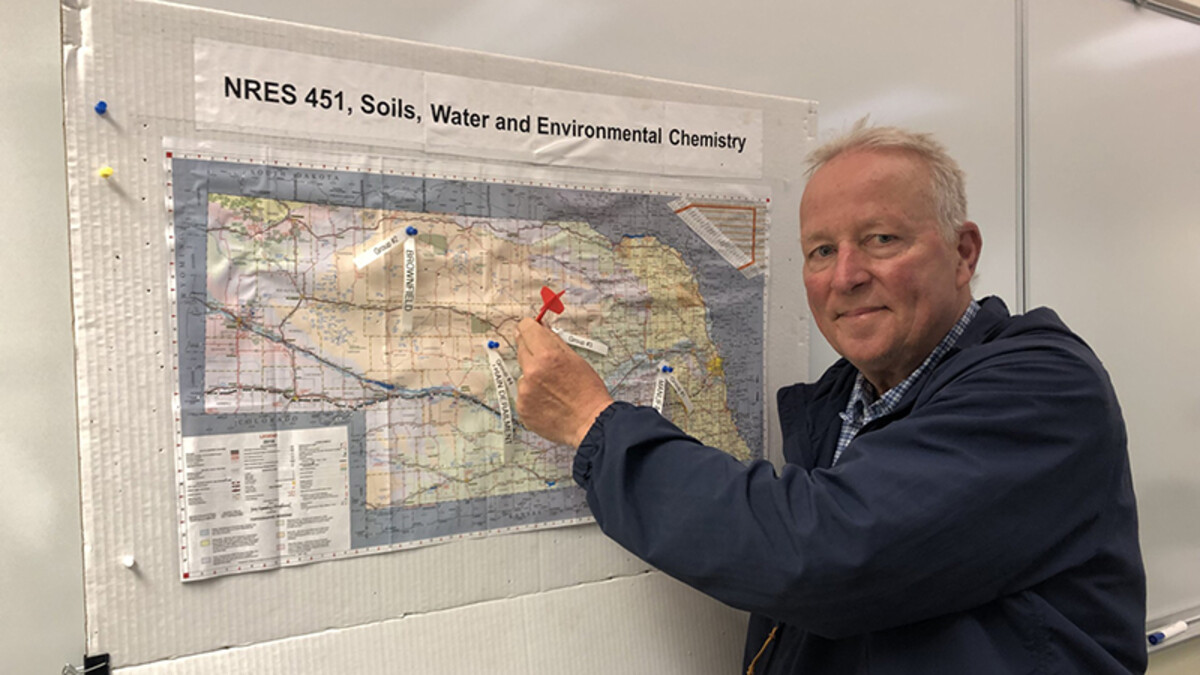 Steve Comfort placing a dart on a map of Nebraska 