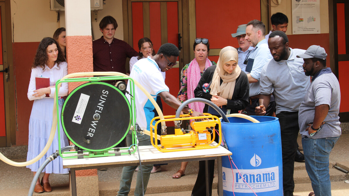 Twelve people gather around a solar-powered water pump at the Don Bosco Solar and Renewable Energy Center in Ghana.