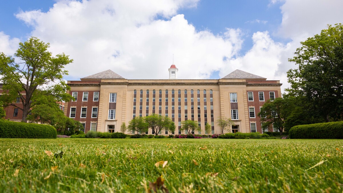 A green lawn is seen south of Love Library South on a partly cloudy day.