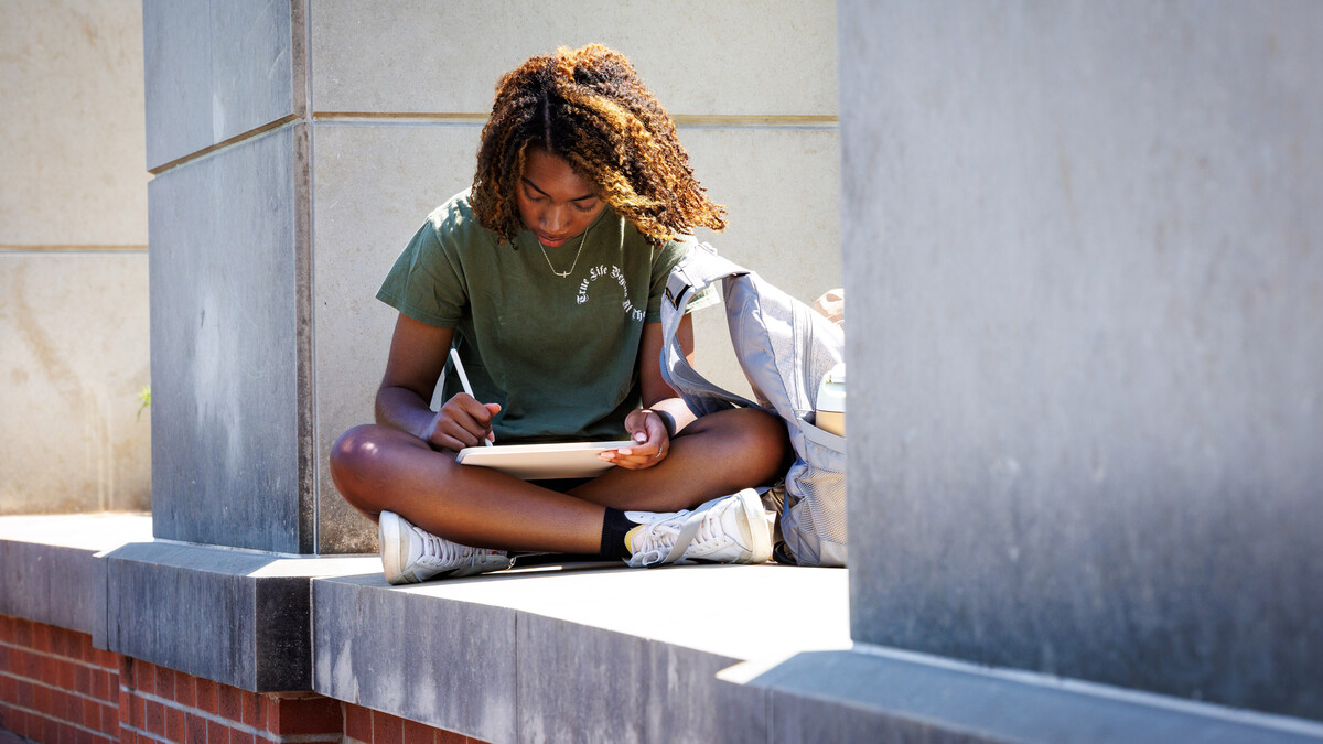 Ayana Robbins, a sophomore graphic design major from Omaha, works on her tablet near the Meier Commons greenspace on May 8.