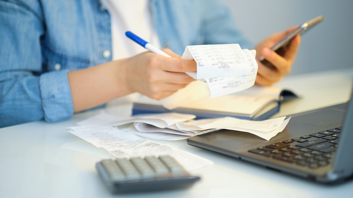 A woman goes through receipts and writes down spending.