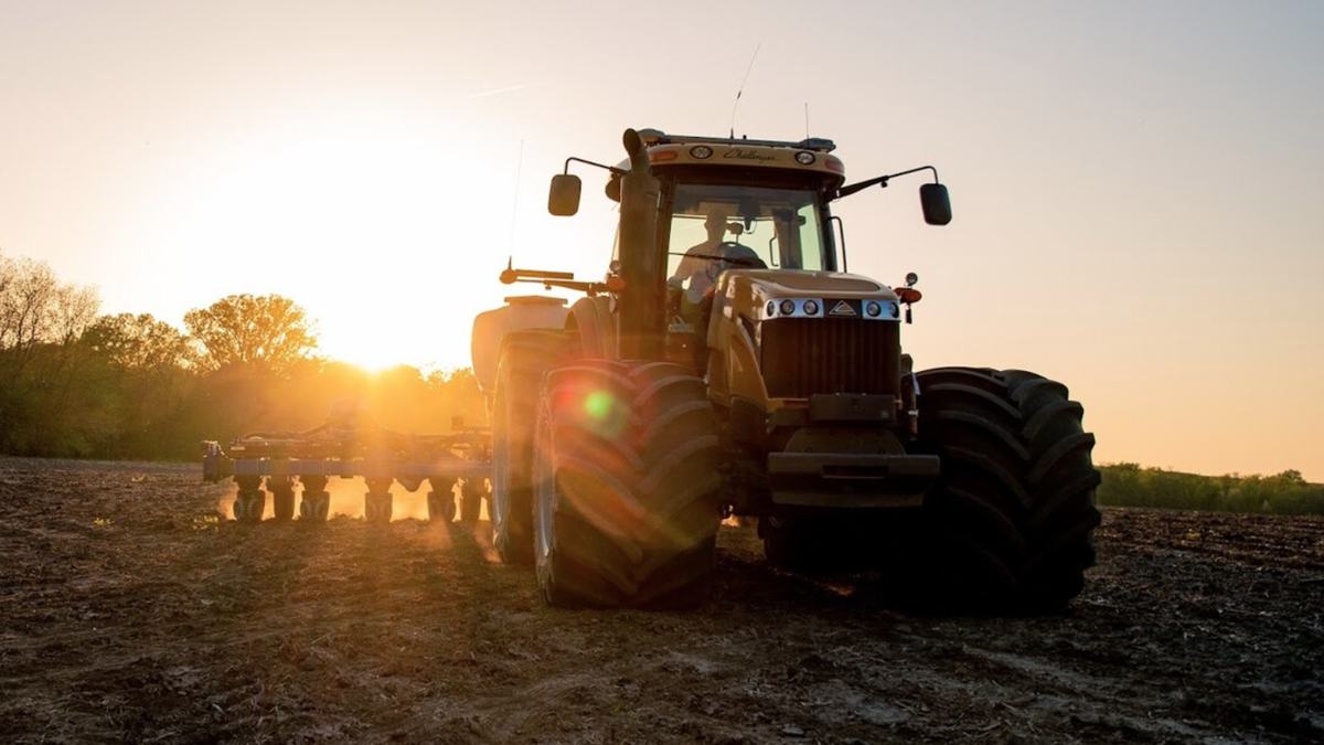 Tractor plowing a field with the sun setting in the background.