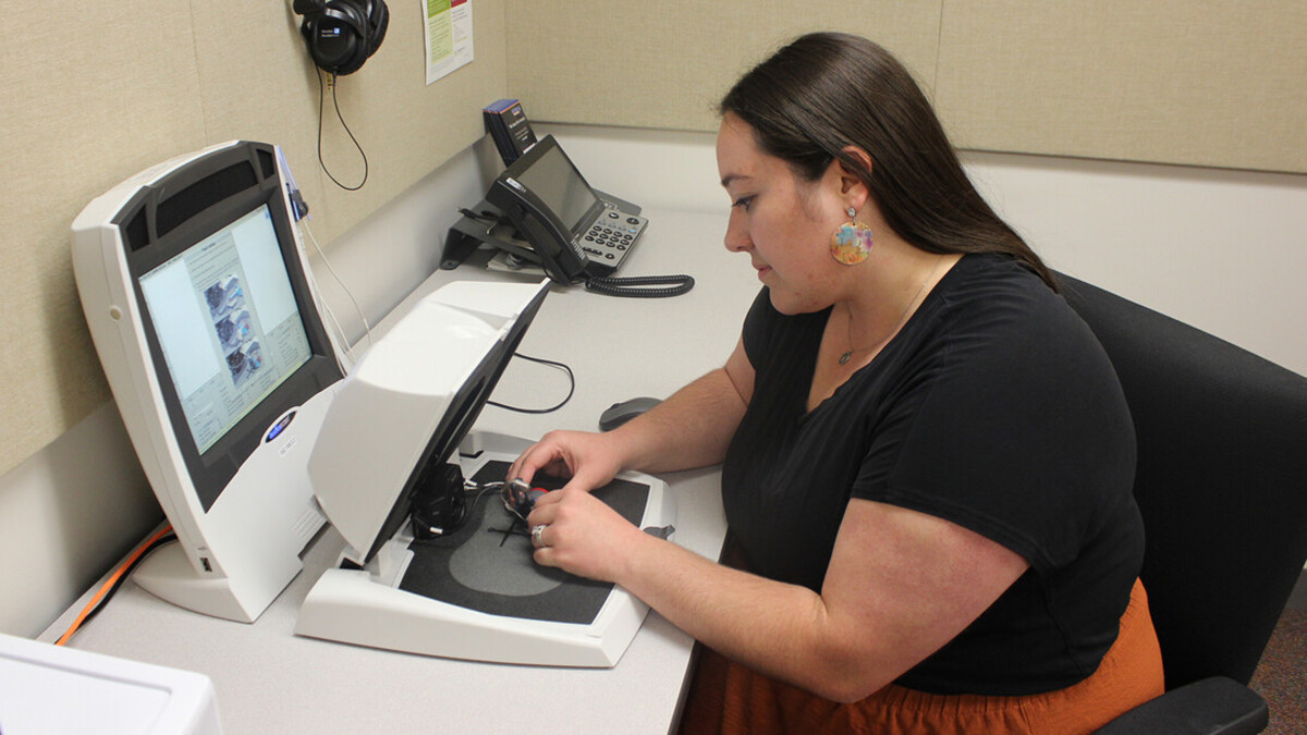 Alli Durnal, a third-year audiology student, places a hearing aid in a Verifit machine at the Barkley Speech Language and Hearing Clinic.