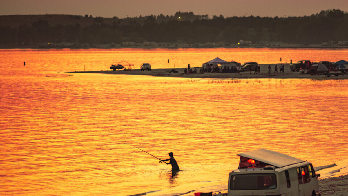 Person fishing in a lake at sunset