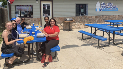 students and program leader at a picnic table outside a rural community business