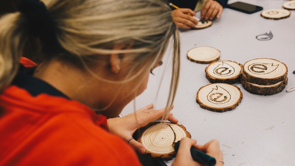 student burning Engler symbol into wood