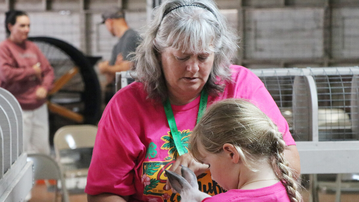 a lady helping a girl with her show rabbit