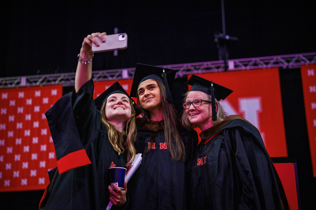 Charlotte Middleton, Sara Alfieri and Dominique Ellis take a selfie onstage after the graduate and professional degree ceremony. They each earned a Master of Fine Arts.