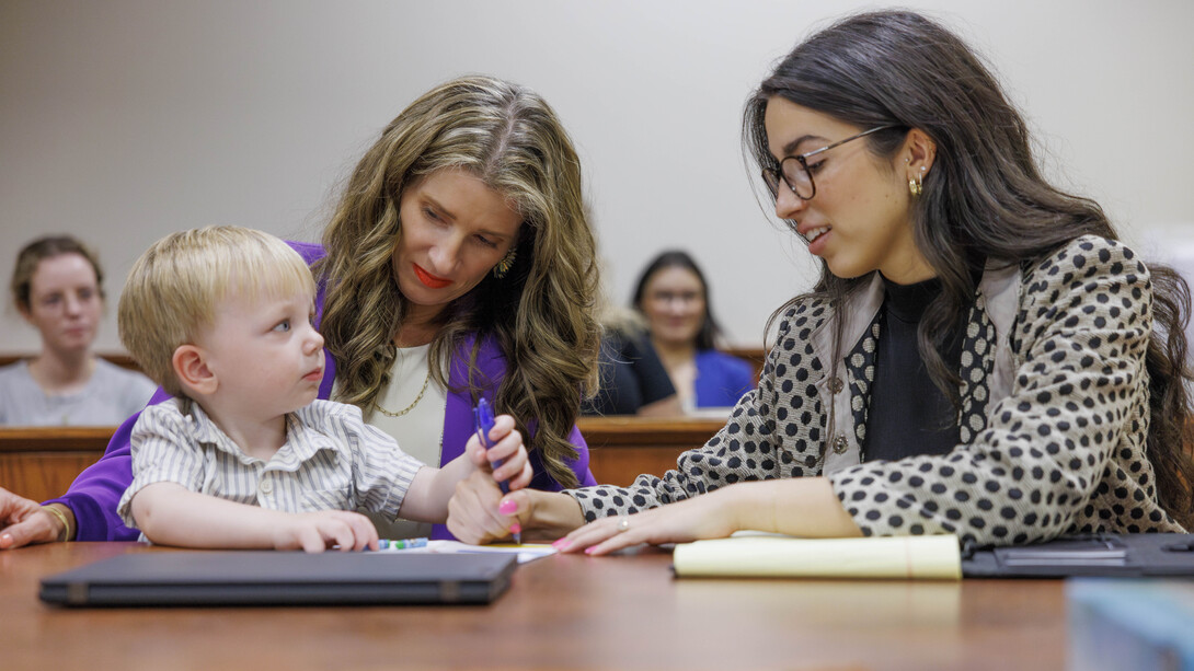 Michelle Paxton (left), director of the Nebraska Children's Justice and Legal Advocacy Center and assistant professor of law, and Carmella Perkins, then a third-year law student, interact with a young boy during a courtroom simulation in August 2024.