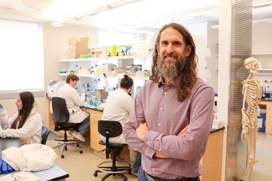 Forrest Kievit, associate professor of biological systems engineering, poses in a lab. He is wearing a red-and-blue plaid shirt and blue slacks.