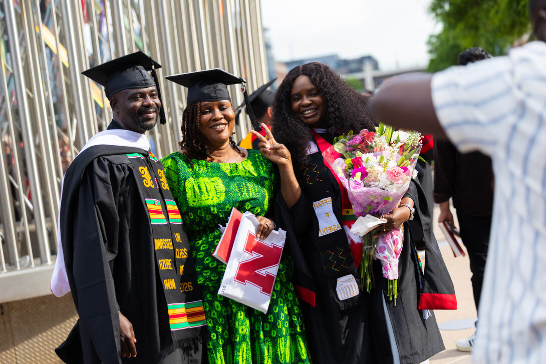 University of Nebraska–Lincoln graduates Manasseh Awuni (left) and Effah Ahiedu (right) pose for a photo with Ahiedu's mother (center) outside Pinnacle Bank Arena.