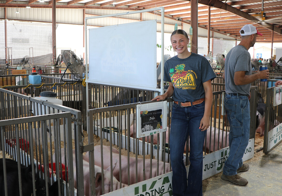 Katelyn Walker standing next to her pigs