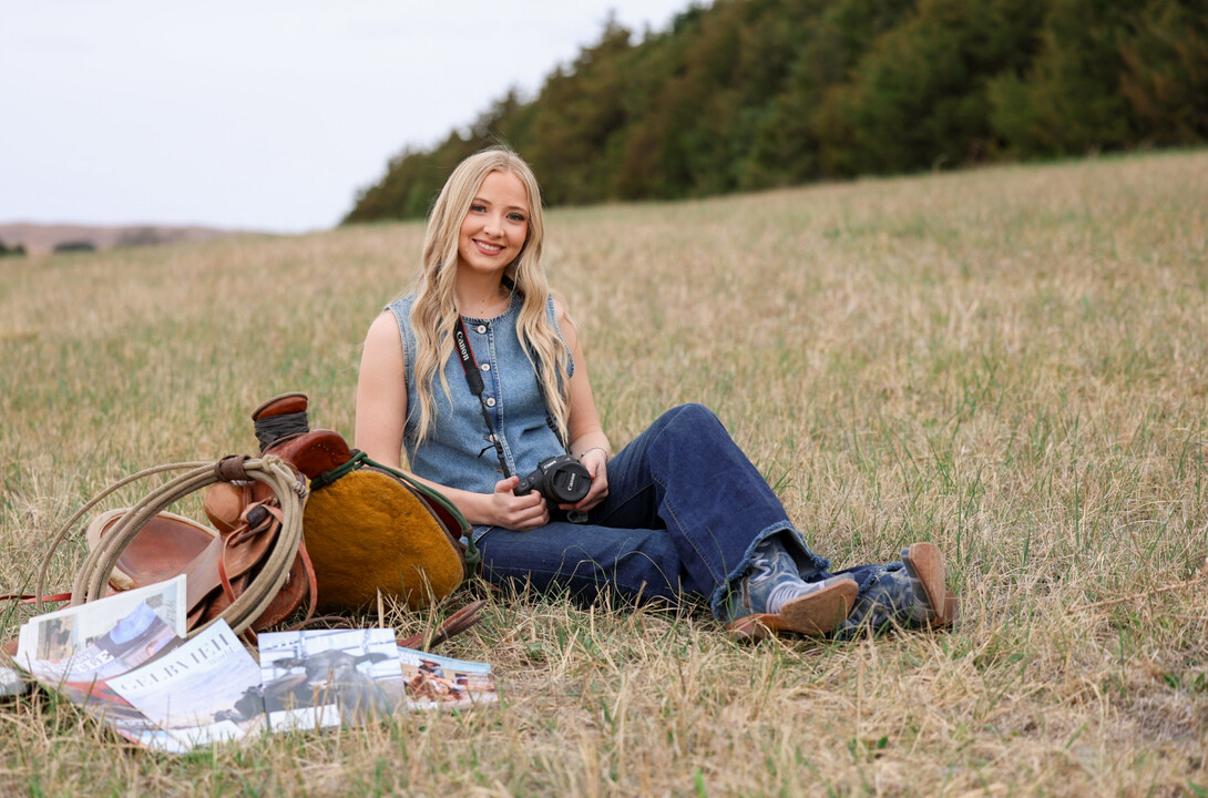 Annalee Starr leans against a saddle, camera in hand
