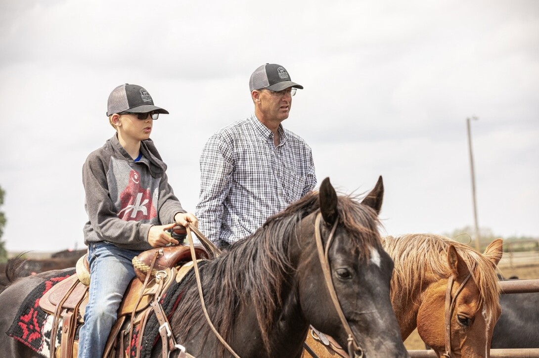 Troy Anderson and son on horses working cattle