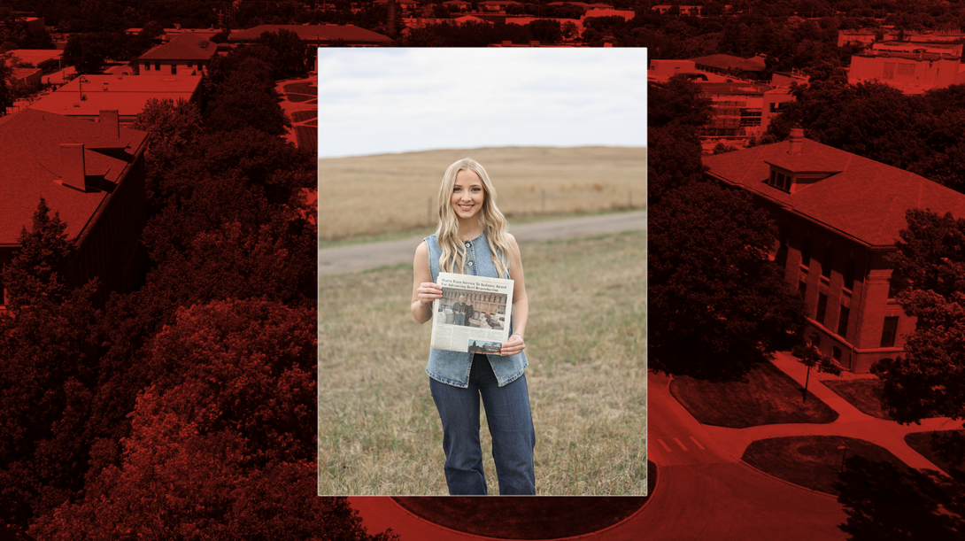 Annalee Starr stands in a pasture, holding a magazine featuring her writing