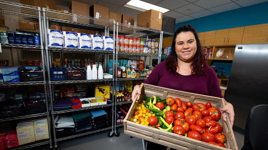 Person holding box of vegetables at the Husker Pantry