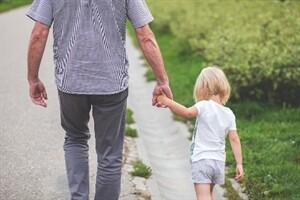 A child holding hands and walking with an adult
