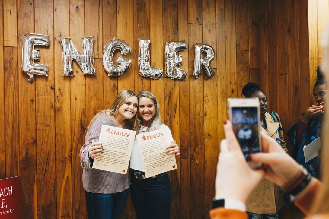 two students posing for a picture underneath balloons that spell out engler