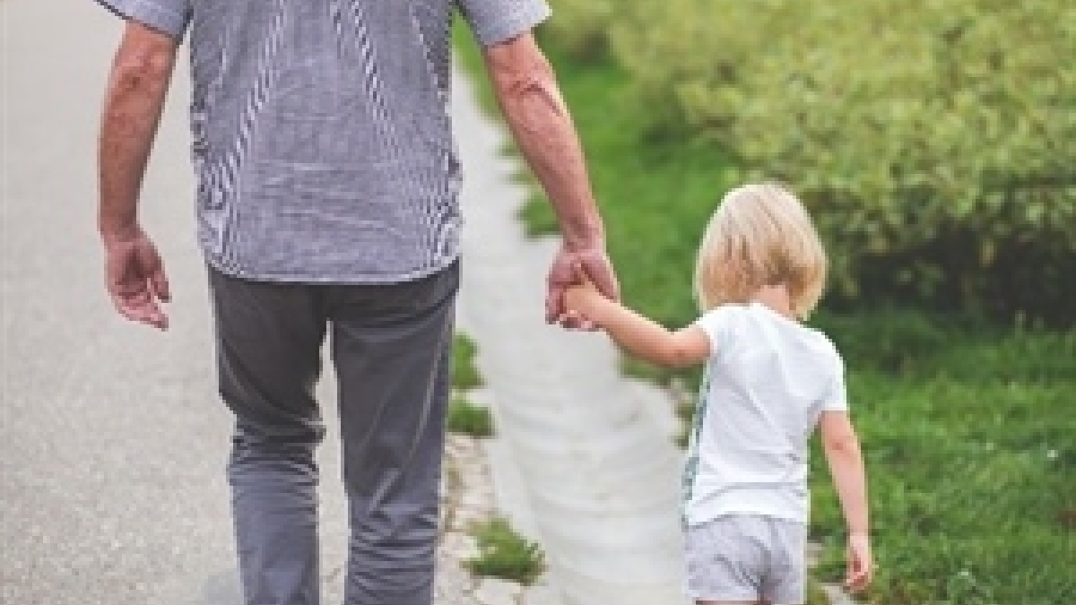 A child holding hands and walking with an adult