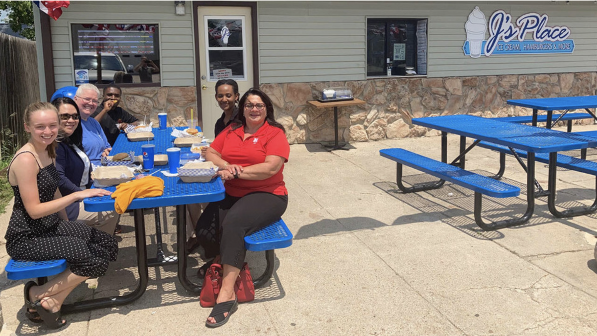 students and program leader at a picnic table outside a rural community business