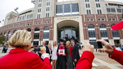 a graduate getting his picture taken in front of memorial stadium during graduation