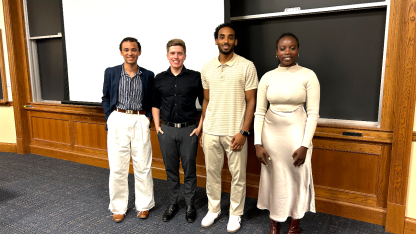 Four people stand in front of a blackboard.